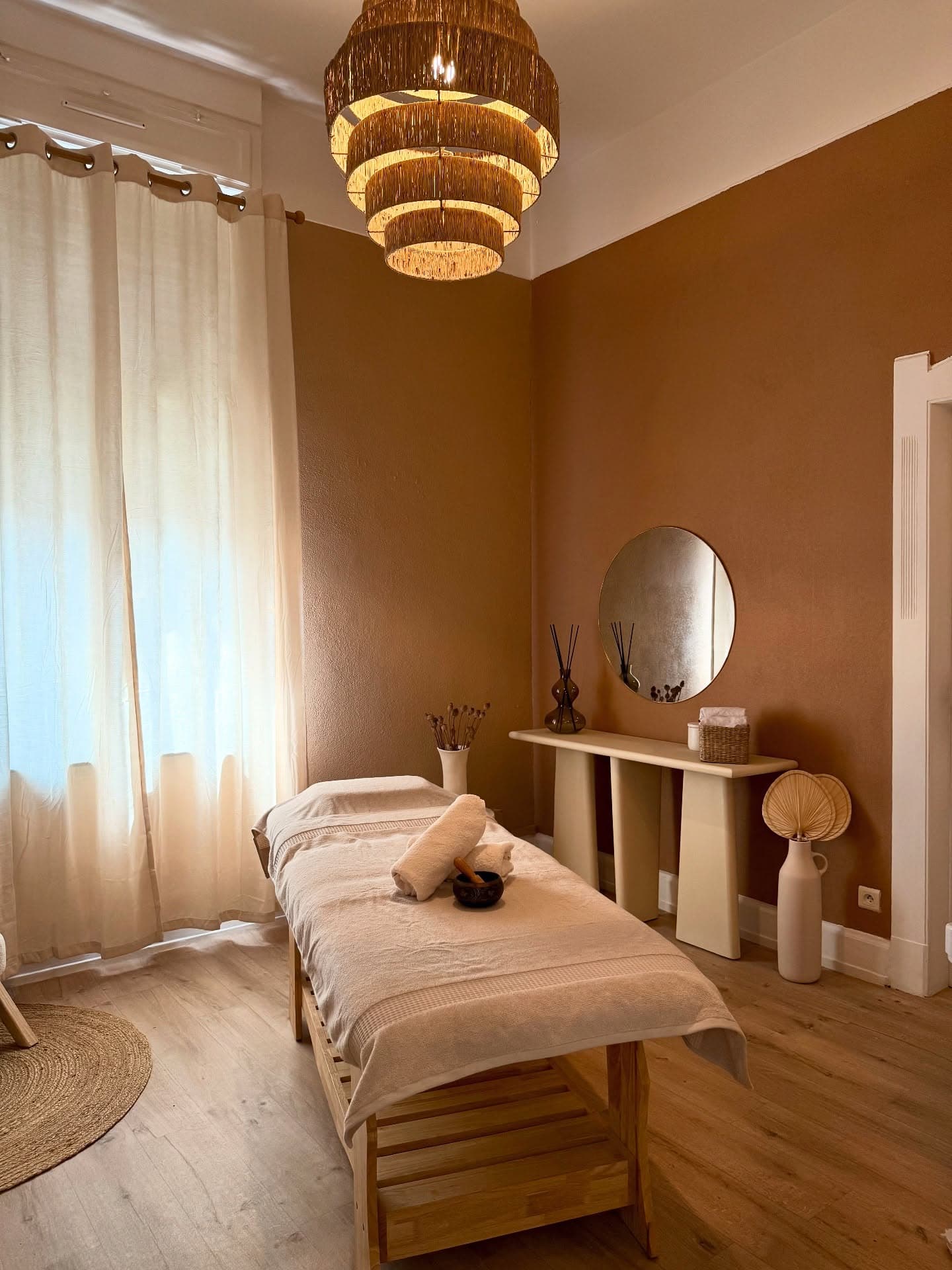 Salle de massage à Thionville : table, fauteuil, suspension en rotin, murs terracotta